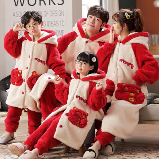 Family of four wearing matching red and cream coral velvet hooded pajamas with embroidered 'money' text and cute pockets.