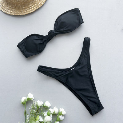 Woman wearing a black bandeau bikini top with a front knot and matching high-cut bottoms, accessorized with gold jewelry. - Image 26