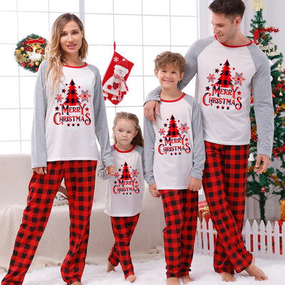 Family of four wearing matching red and black buffalo plaid Christmas pajamas with white and grey raglan tops.