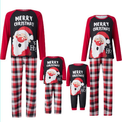 Family matching Christmas pajamas with Santa Claus graphic and "Merry Christmas!" text on black and red tops, paired with red and black plaid pants.