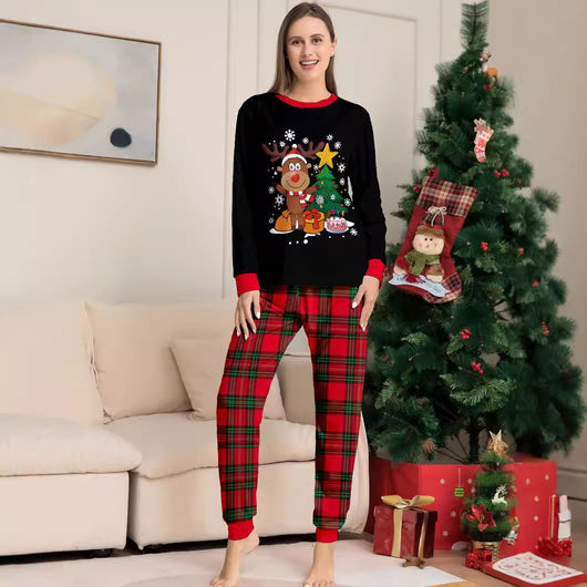 Two children in black and red plaid Christmas pajamas with a reindeer and Christmas tree graphic, standing by a Christmas tree. - Image 4