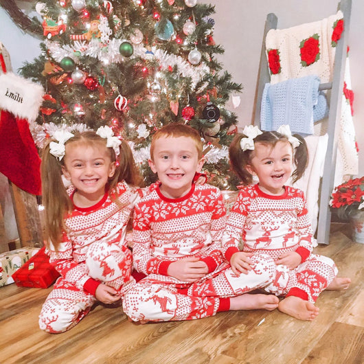 Family of seven wearing matching red and white Christmas pajamas with reindeer and snowflake patterns in a living room. - Image 7