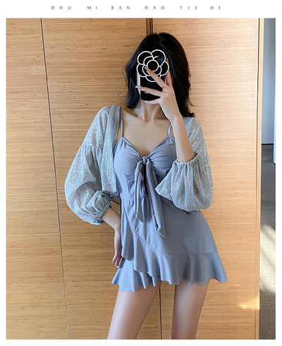 Women's light blue one-piece swimsuit with tie-front bust and ruffled hem, paired with a sheer shimmery cover-up. - Image 11