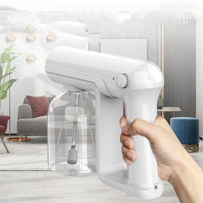 Black wireless alcohol blue light disinfection spray gun with clear reservoir, actively misting, on a marble surface. - Image 3