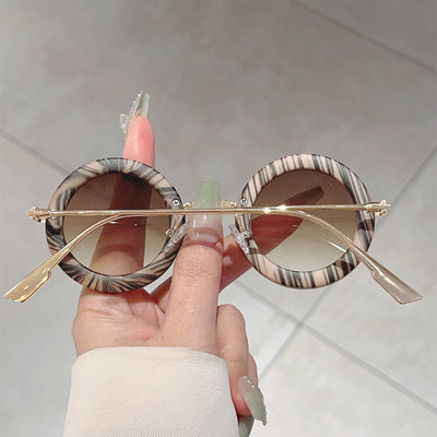 Small frame oval fashion sunglasses with black frames and vibrant orange lenses, held by a hand. - Image 16