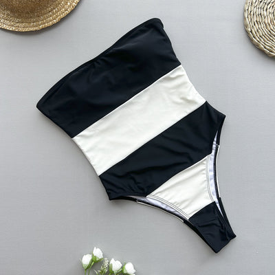 Women's black and white striped strapless one-piece swimsuit with a high-cut leg, modeled outdoors. - Image 3