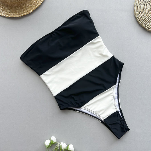 Women's black and white striped strapless one-piece swimsuit with a high-cut leg, modeled outdoors. - Image 3