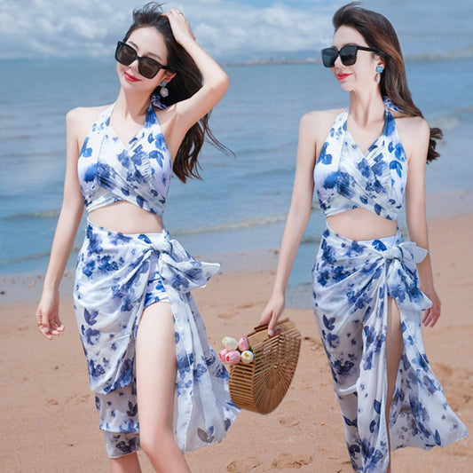 Women's light blue tropical leaf print three-piece swimsuit with short sleeve bikini top, bottoms, and sarong skirt.