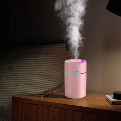 Pink cylindrical humidifier with a colorful LED light ring on top and a blue-green light band around its middle. - Image 14