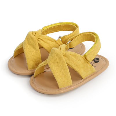 Black baby sandals with knotted cross straps and a matching black floral headband on a white background. - Image 16