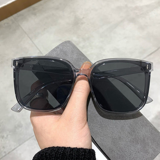 Two pairs of square-frame sunglasses, one with a cream frame and dark lenses, the other with a translucent brown frame and brown lenses.