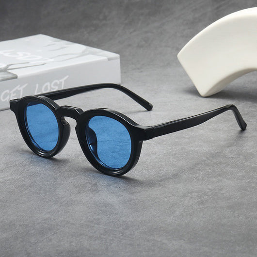 Vintage round frame sunglasses with black frames and pink lenses on a gray surface. - Image 9
