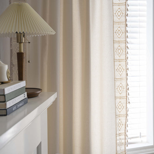 Close-up of a beige semi-transparent curtain with a delicate crochet lace trim and decorative tassels. - Image 3