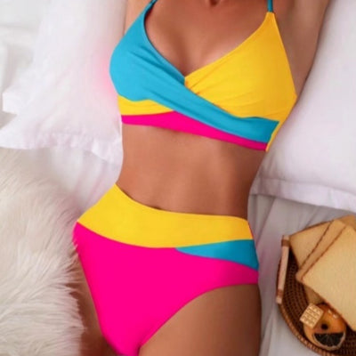 Woman wearing a blue color block split swimsuit with a wrapped front bikini top and high-waisted briefs.