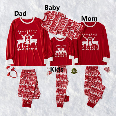 Family of four wearing matching red Christmas pajamas with white reindeer and tree patterns, standing by a decorated tree. - Image 8