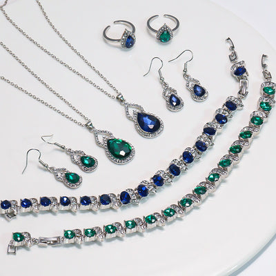 Light luxury jewelry set with silver-tone necklace, dangle earrings, open ring, and bracelet, all featuring emerald green teardrop and oval stones with clear rh - Image 9