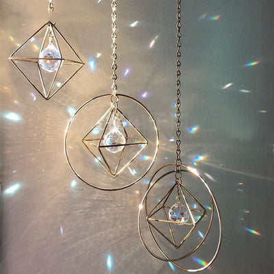 Geometric iridescent suncatcher with a gold frame and dangling crystal pendants, held in a hand, creating rainbow light. - Image 11