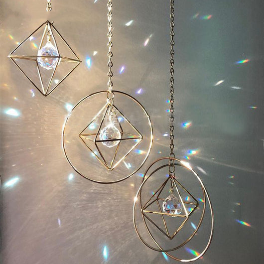 Geometric iridescent suncatcher with a gold frame and dangling crystal pendants, held in a hand, creating rainbow light. - Image 11