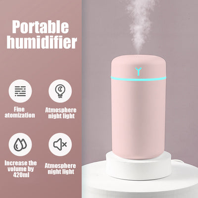 Pink portable humidifier with a blue LED light band, emitting fine mist, on a white pedestal. - Image 6