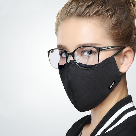 Woman wearing a pink cotton face mask with light blue polka dots and bow patterns, paired with black-framed glasses. - Image 7