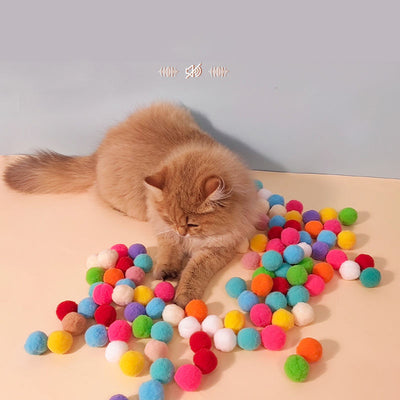 Colorful pompom balls and a yellow and blue toy launcher, a fun set for cats or kids.
