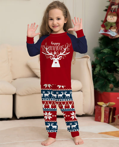 Child wearing a red and navy blue Christmas pajama set with a white reindeer and "happy NEW YEAR" text on the top, and fair isle pattern pants. - Image 4