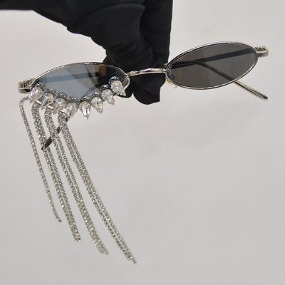 Silver oval-frame sunglasses with mirrored lenses and glamorous rhinestone tassels on one side, held by a gloved hand. - Image 2