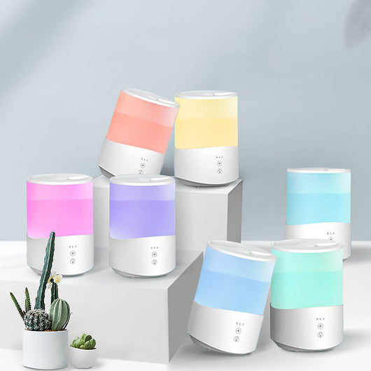 White cylindrical household humidifier with a translucent top section glowing blue, featuring two control buttons. - Image 7