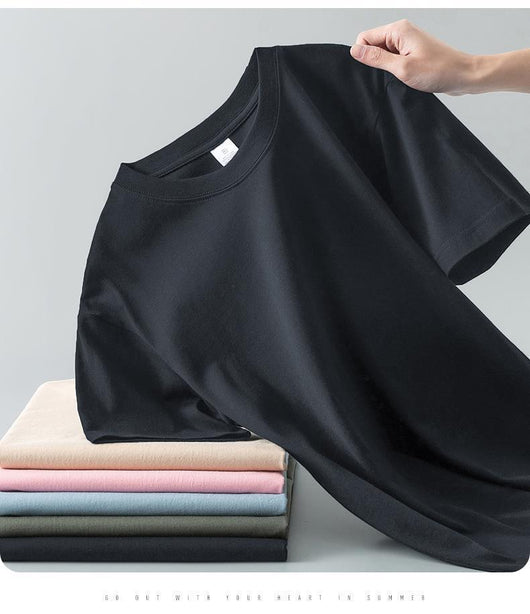 Light gray short-sleeve t-shirt with a round neck, held up to show its smooth fabric. A stack of folded t-shirts in various colors is visible in the background. - Image 25