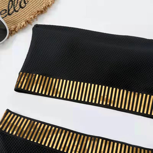 Black bandeau bikini with gold striped trim and matching high-waisted bottoms on a white surface. - Image 3