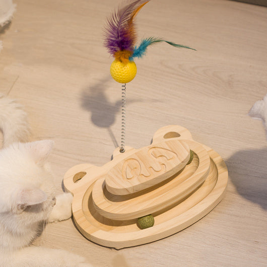 White cat playing with a wooden multi-level track toy featuring a spring-mounted yellow feather ball and a green catnip ball. - Image 11