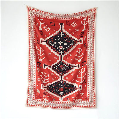 Red tapestry with black and white geometric tribal pattern hanging on a white wall above decorative pillows. - Image 9