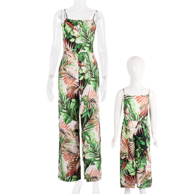Mother and two daughters in matching green tropical print jumpsuits, posing outdoors in a sunny resort setting. - Image 11