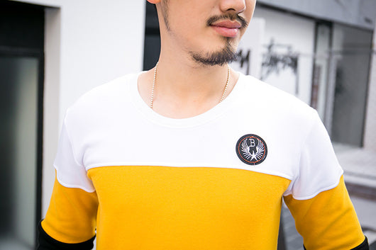 Men's white and yellow color block long-sleeve top with a crew neck and circular embroidered patch on the chest. - Image 3