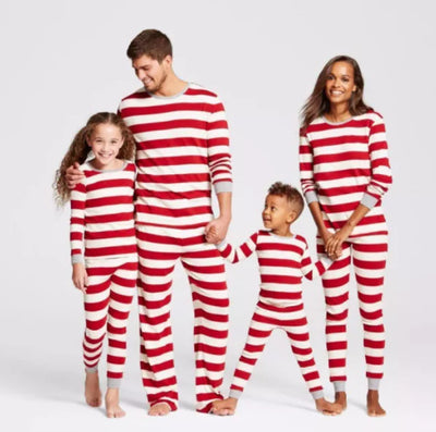 Family of four in matching red and white striped Christmas pajamas, sitting on a white rug with holiday decor. - Image 11