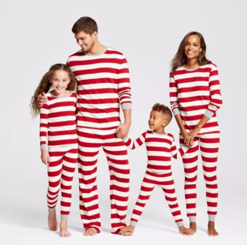 Family of four in matching red and white striped Christmas pajamas, sitting on a white rug with holiday decor. - Image 11
