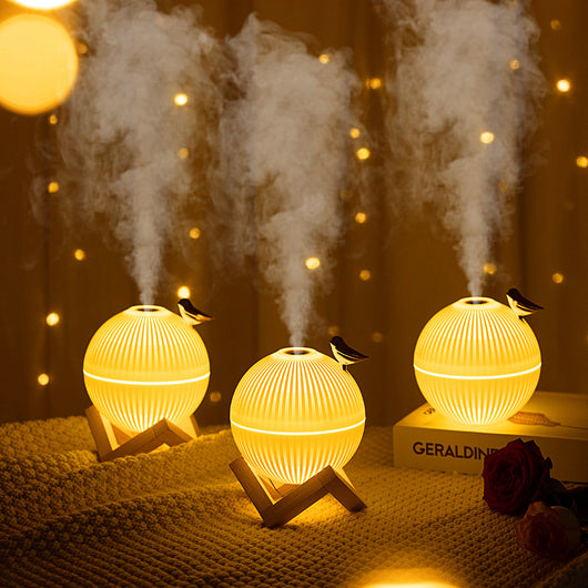 White spherical humidifier with ribbed texture, warm glow, metallic bird accent, and light brown wooden stand. - Image 9