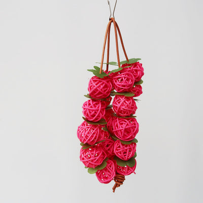 Pink woven rattan ball parrot chew toy with green leaf accents, hanging from a metal hook. - Image 3