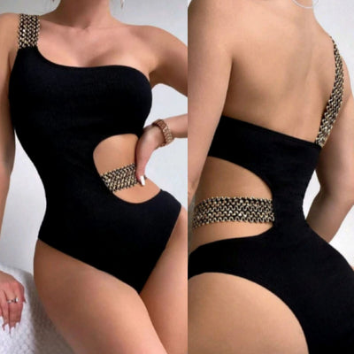 Black one-shoulder one-piece swimsuit with side cut-outs and gold chain-link detailing on strap and waist.
