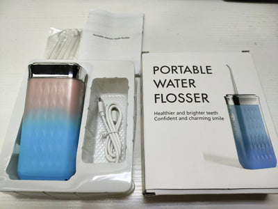 Portable water flosser in gradient pink and blue with four nozzles, a charging cable, and its product box. - Image 43