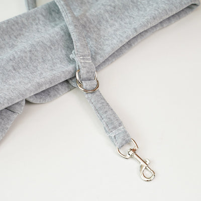 Person in white hoodie carrying a happy white dog in a navy blue pet sling bag outdoors. - Image 22