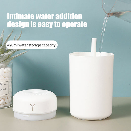 Pink portable humidifier with a blue LED light band, emitting fine mist, on a white pedestal. - Image 3