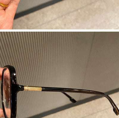 Black oversized square anti-blue light glasses with clear resin lenses and gold metal frame details, held by a hand. - Image 3