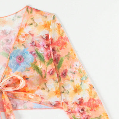 Four-piece women's beachwear set with a peach, blue, and green floral print. Includes a triangle bikini, long-sleeve tie-front cover-up, and ruched mini skirt. - Image 12