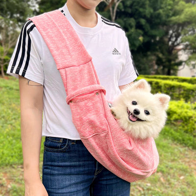 Person in white hoodie carrying a happy white dog in a navy blue pet sling bag outdoors. - Image 48