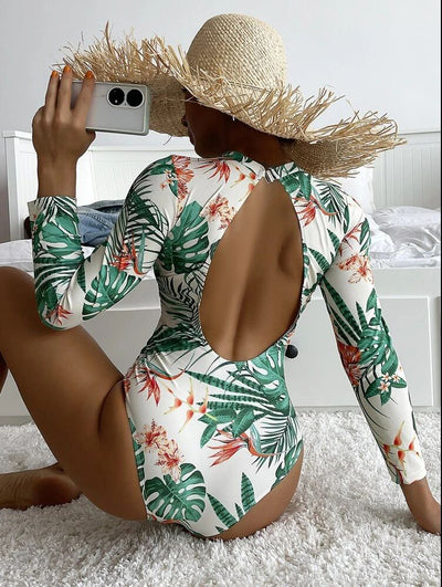 Women's pink long-sleeve one-piece swimsuit with a vibrant tropical leaf and floral print. - Image 3