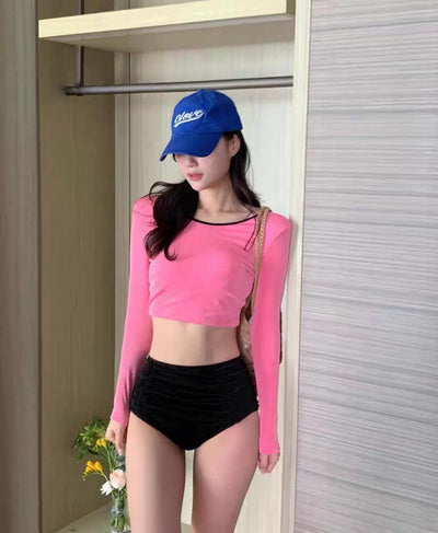 Woman in a pink long-sleeved crop top and black high-waisted ruched swim bottoms, posing in a mirror. - Image 9