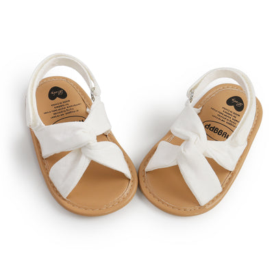 Black baby sandals with knotted cross straps and a matching black floral headband on a white background. - Image 31