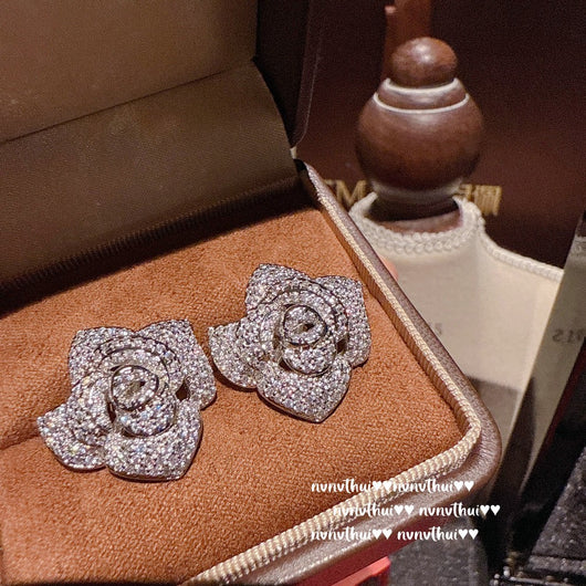 Pair of sparkling rose-shaped stud earrings, encrusted with clear gemstones, displayed in a brown jewelry box. - Image 9
