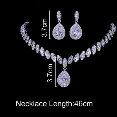Silver-toned necklace and earring set with red teardrop stones and clear marquise-cut accents on a black display. - Image 9